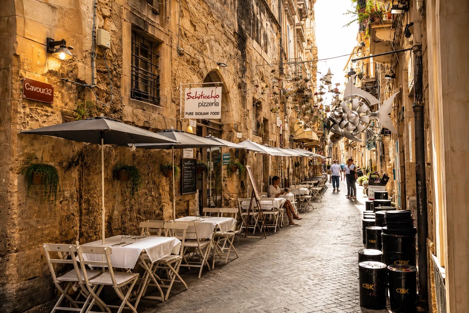 The Schiticchio pizzeria sign and terrace on a narrow Ortigia street.