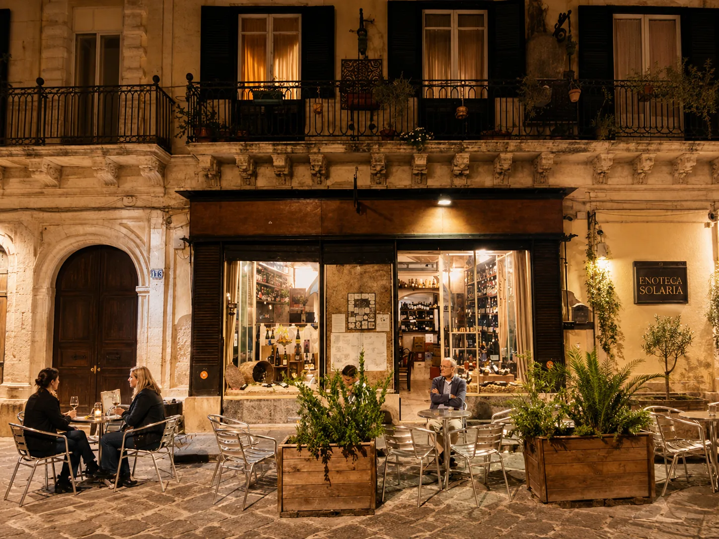 The warmly lit Enoteca Solaria storefront and outdoor tables at night.